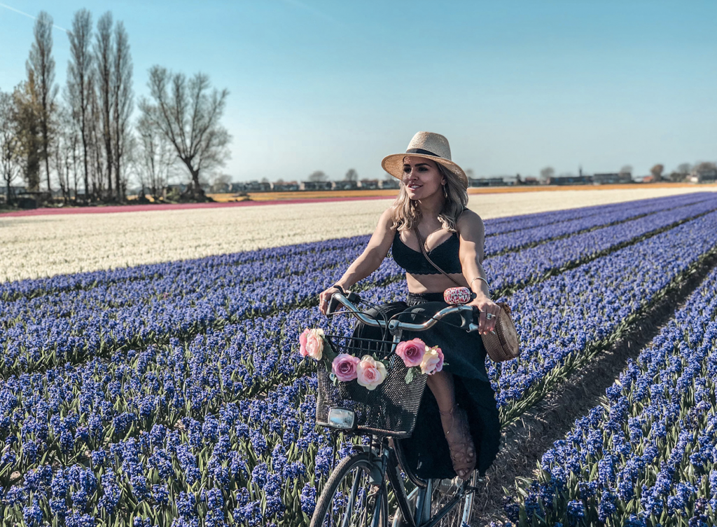 Imagem da Adelia Nerys andando de bicicleta pelo campo de tulipas.