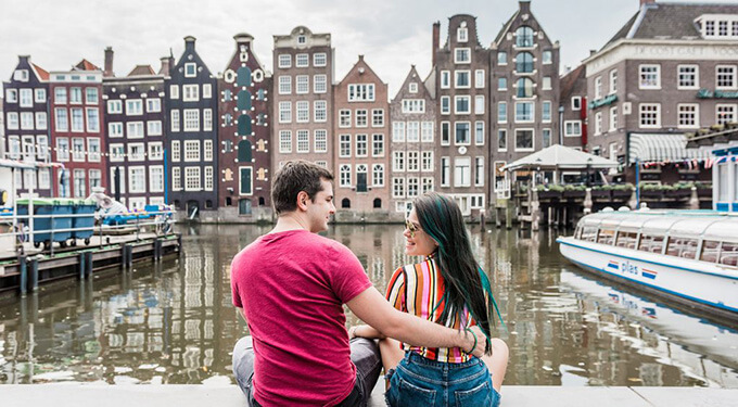 Imagem de casal pozando para foto em canais de amsterdam